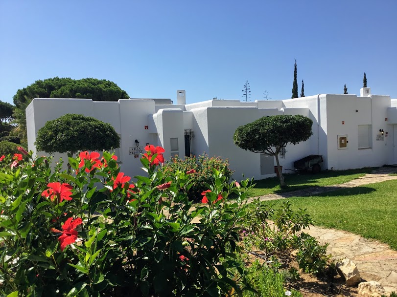 Prado VIllas exterior of villas surrounded by grass and red hibiscus flowers